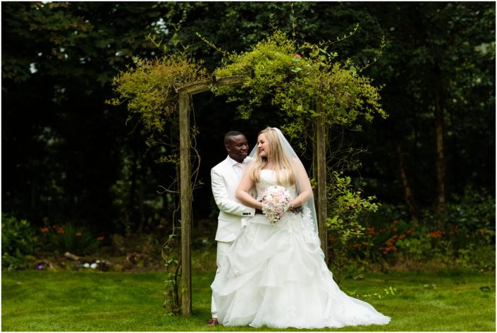 Francis and Jenifers wedding day bride and groom posing together in front of wooden frame